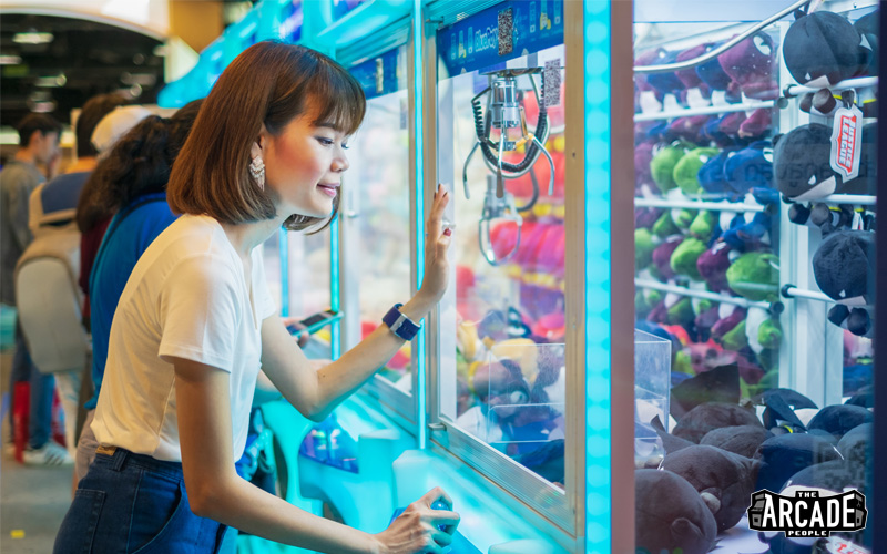Lady using a claw machine at the arcade people in singapore